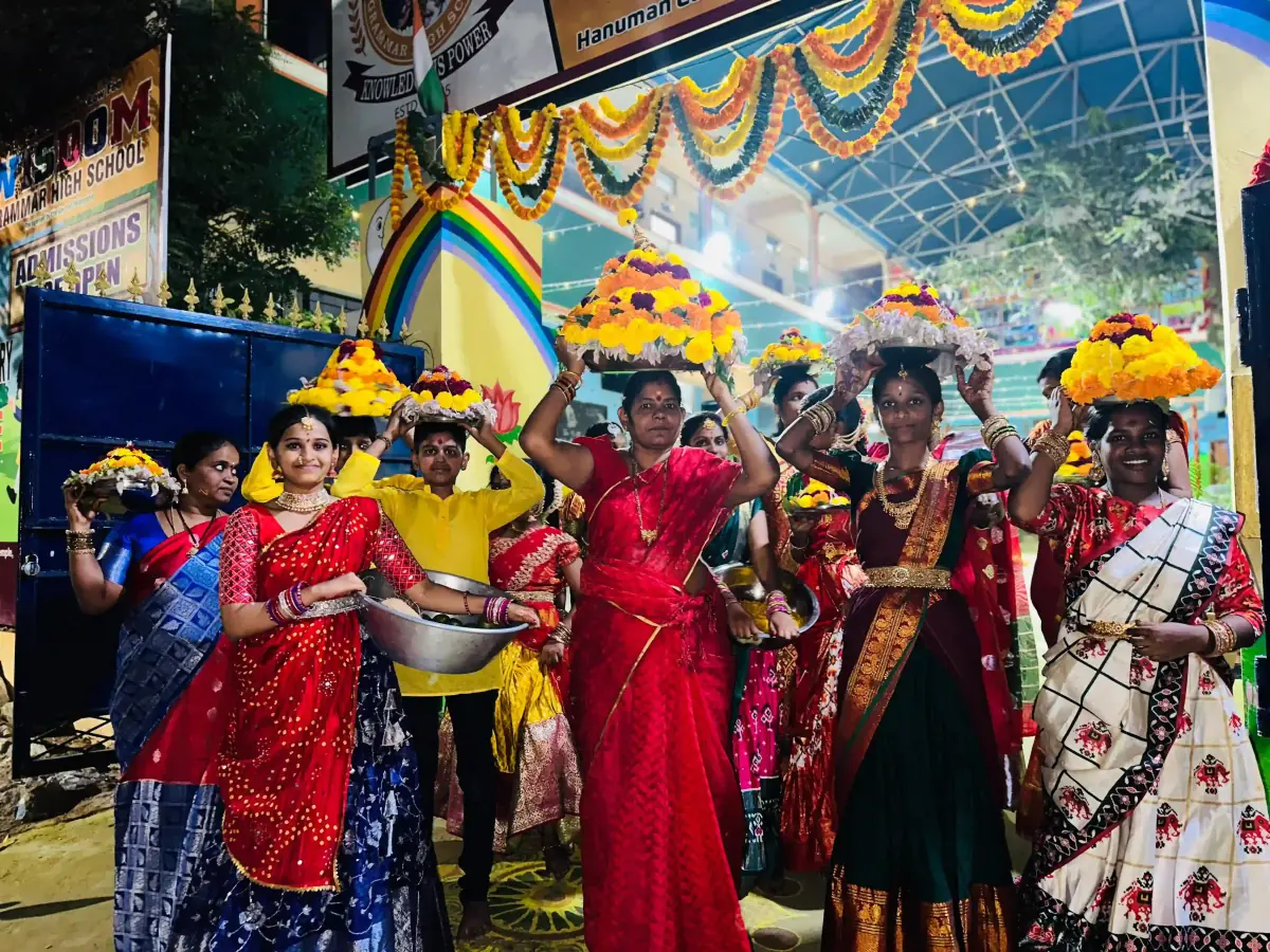 Students participating in Bathukamma with flower arrangements